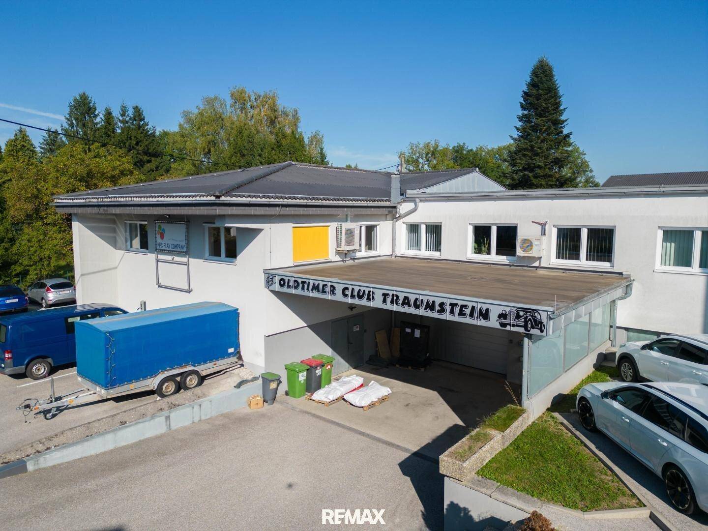 Gewerbegebäude des Oldtimer Clubs Traunstein mit überdachtem Eingangsbereich und Parkplätzen.