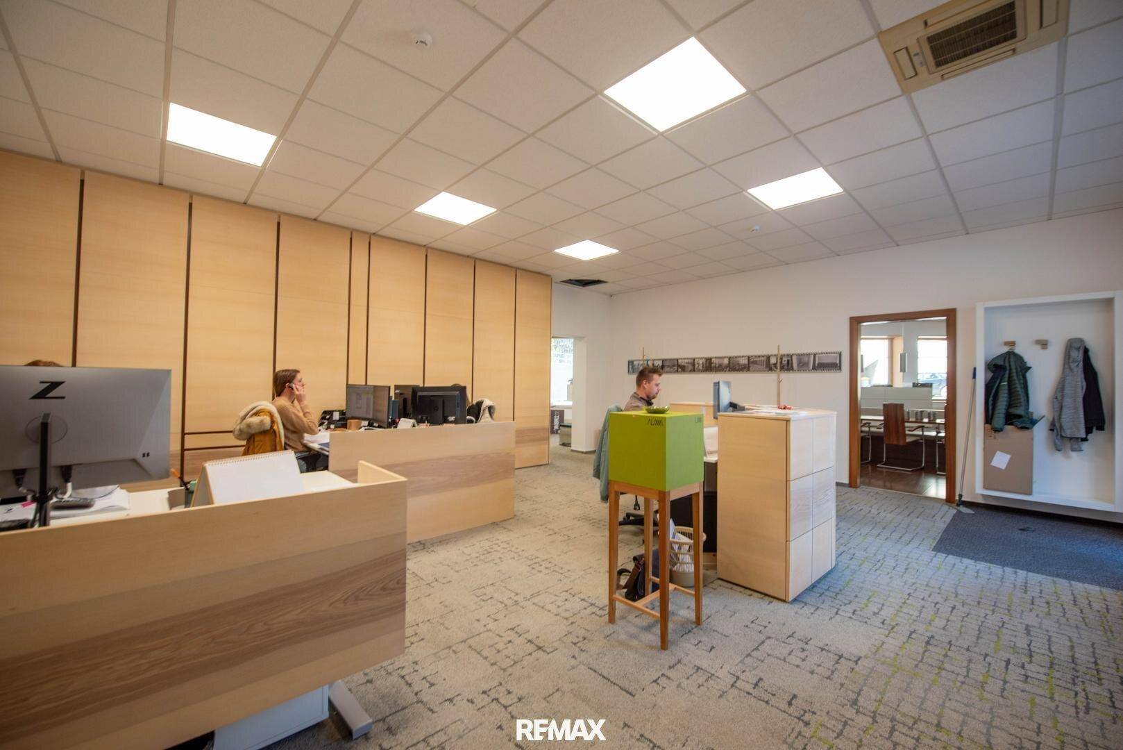 Helles und geräumiges Büro mit Holzvertäfelung, Teppichboden und modernen Arbeitsplätzen.
