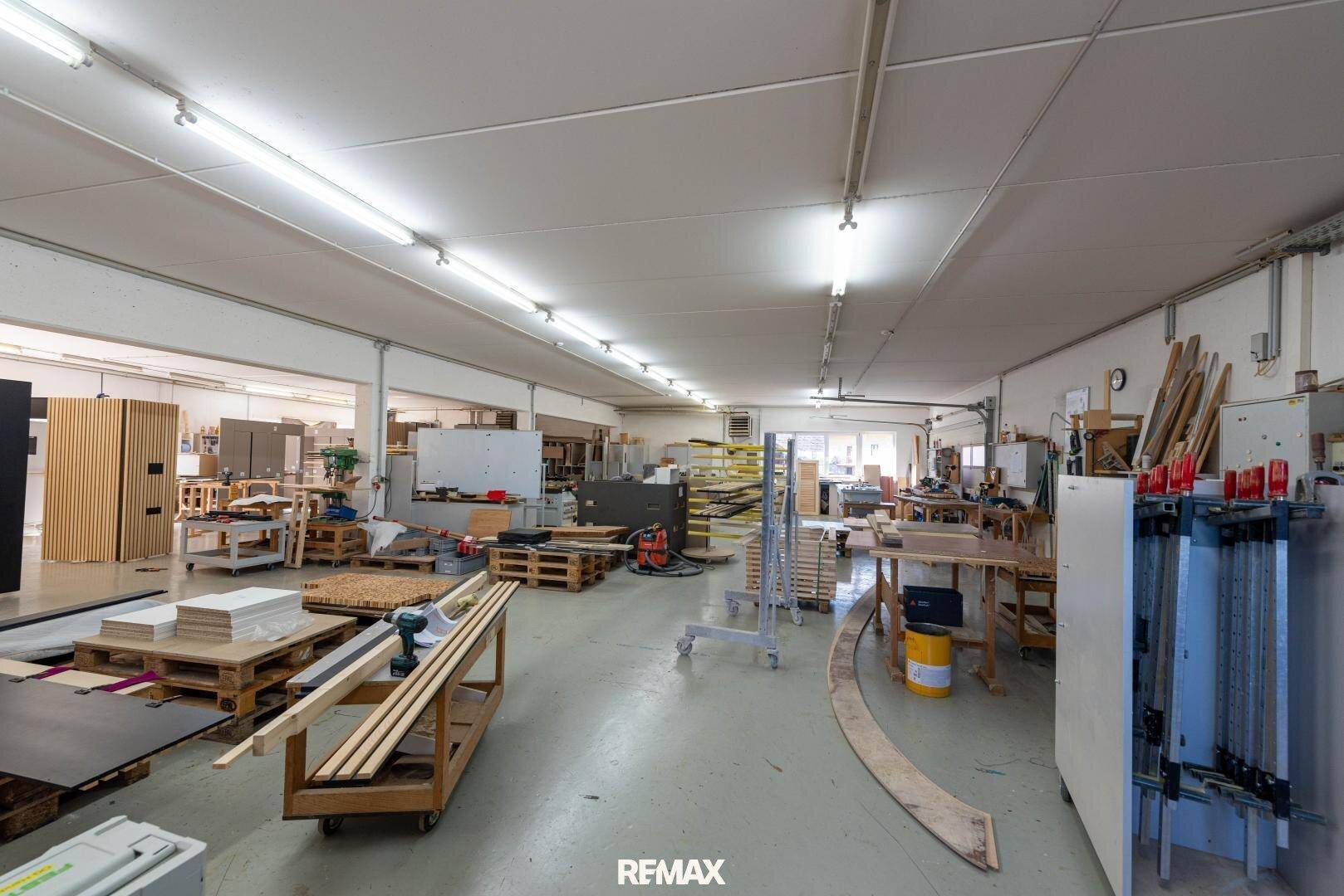 Weitläufige Werkstatt mit verschiedenen Holzbearbeitungsmaschinen und Materialien für die Produktion.