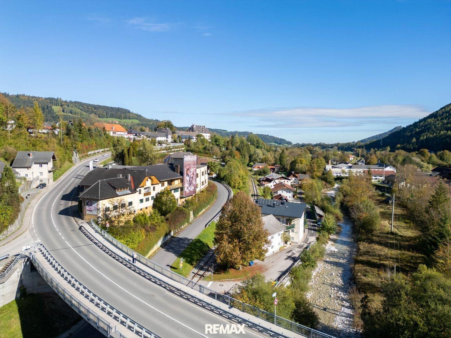 Weitläufige Luftaufnahme der ländlichen Umgebung mit Straßen, Brücken und Gebäuden inmitten von Wäldern.