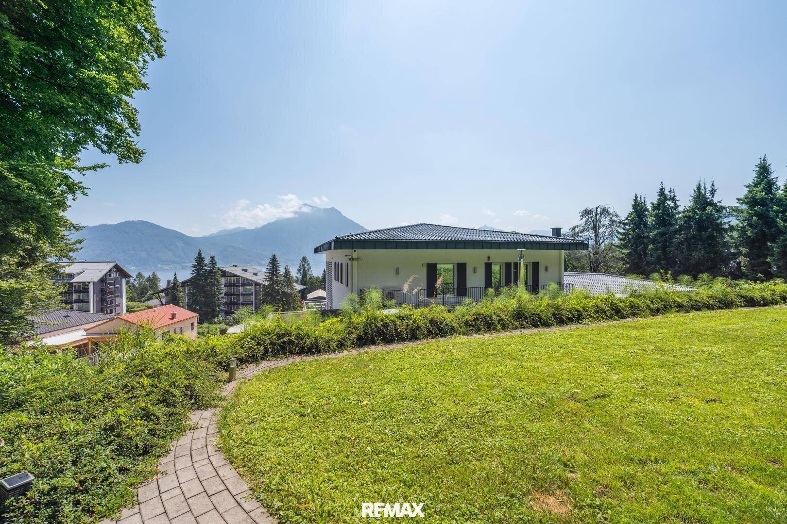 Gepflegter Gartenbereich mit Rasenfläche, Steinweg und Panoramablick auf die umliegende Berglandschaft.