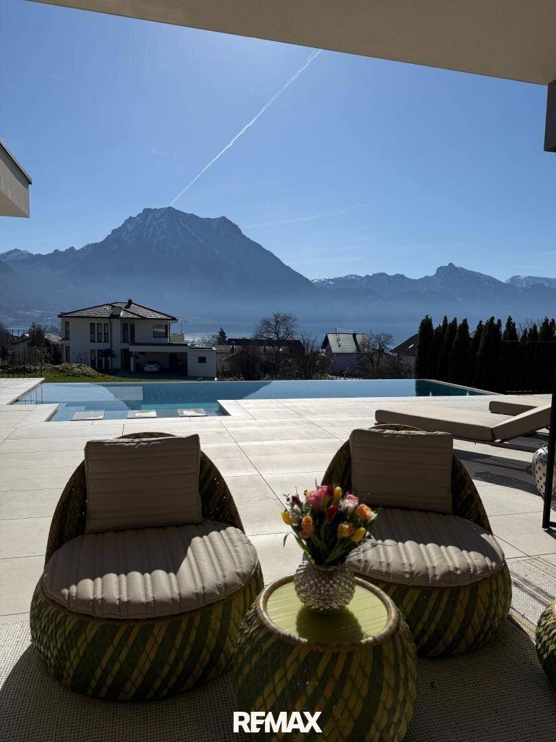 Gemütlicher Außenbereich mit Sitzgelegenheiten und weitem Blick auf den See und die Berge.
