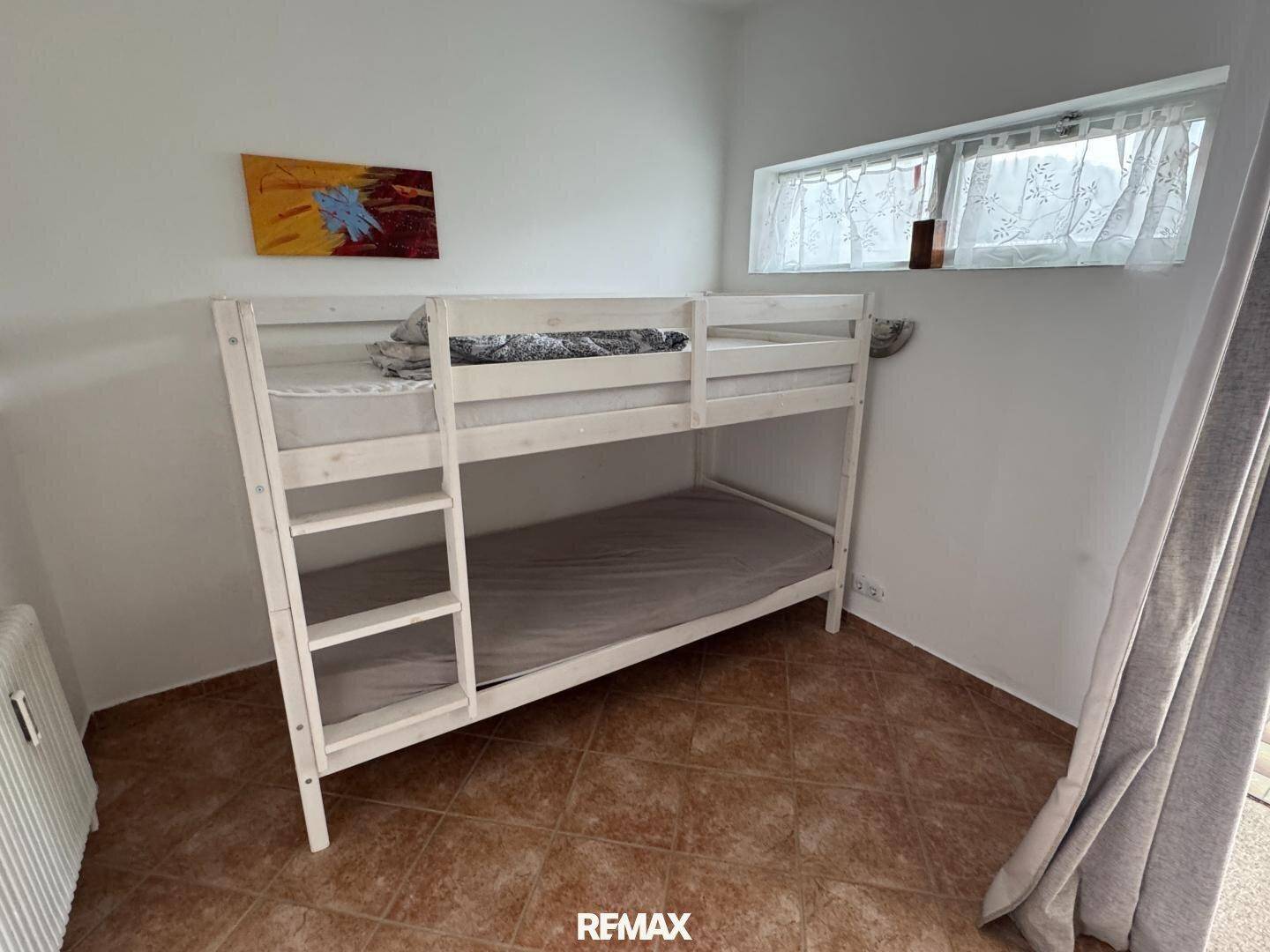 Kinderzimmer mit Etagenbett und Fliesenboden, hell und funktional eingerichtet.