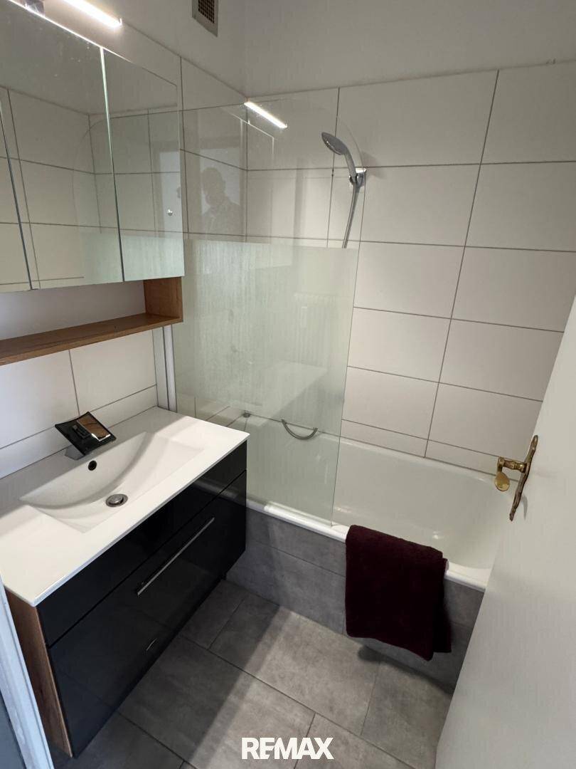Helles Badezimmer mit Badewanne, Duschabtrennung und modernem Waschtisch.
