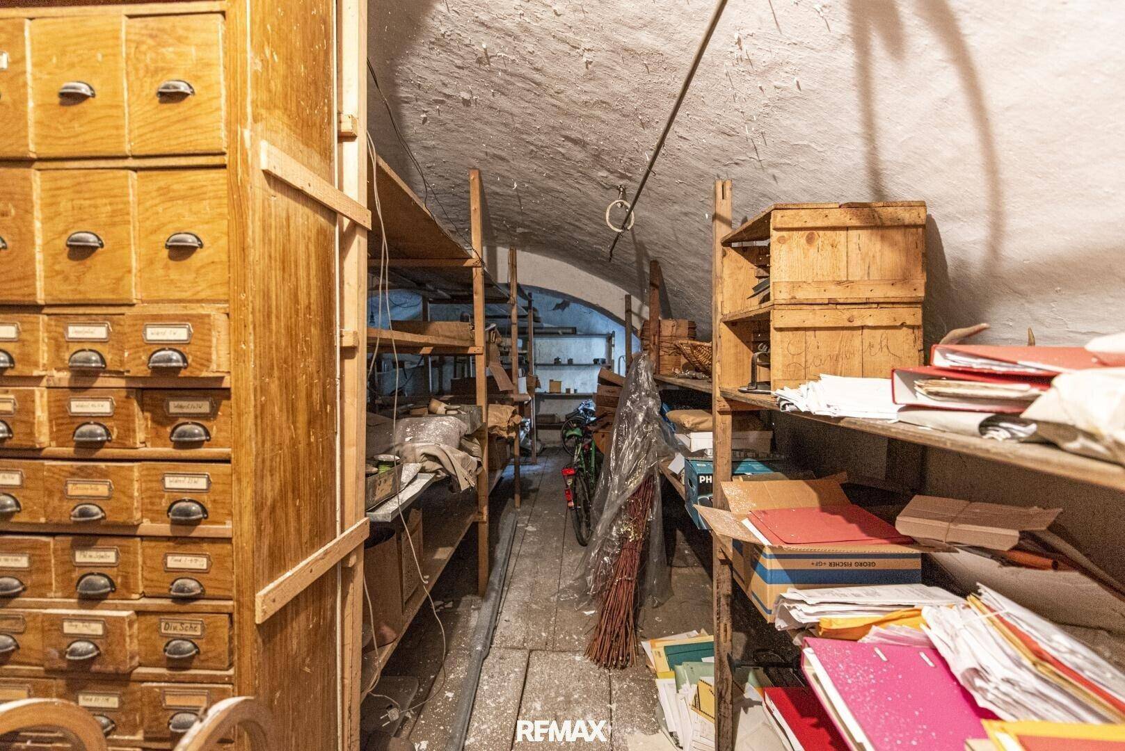 Langer Lagerraum oder Keller mit vielen Holzregalen und Archivschränken, ideal für Aufbewahrung.