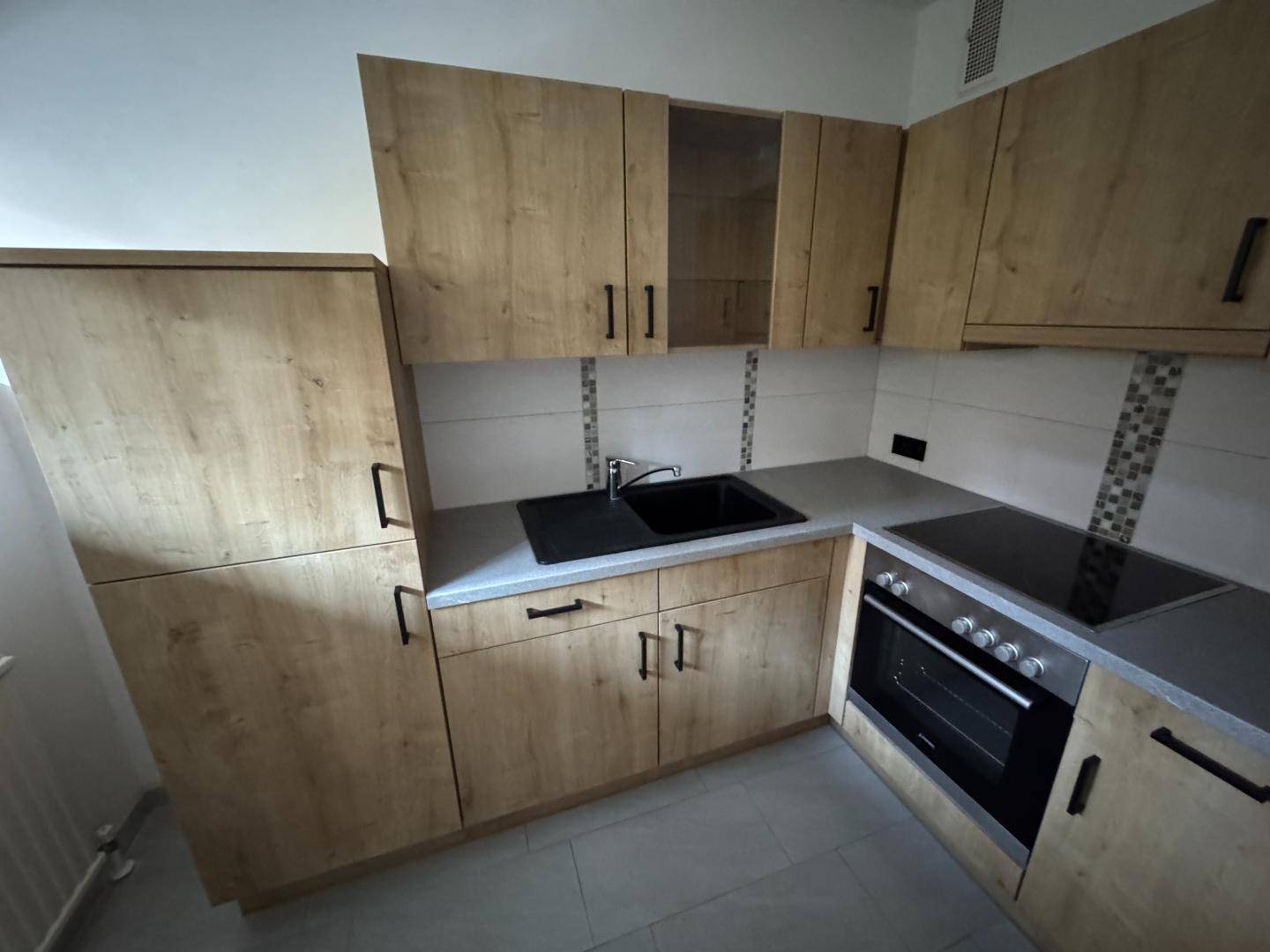 Neue Einbauküche mit holzfarbenen Schränken, schwarzer Spüle und modernen Elektrogeräten.