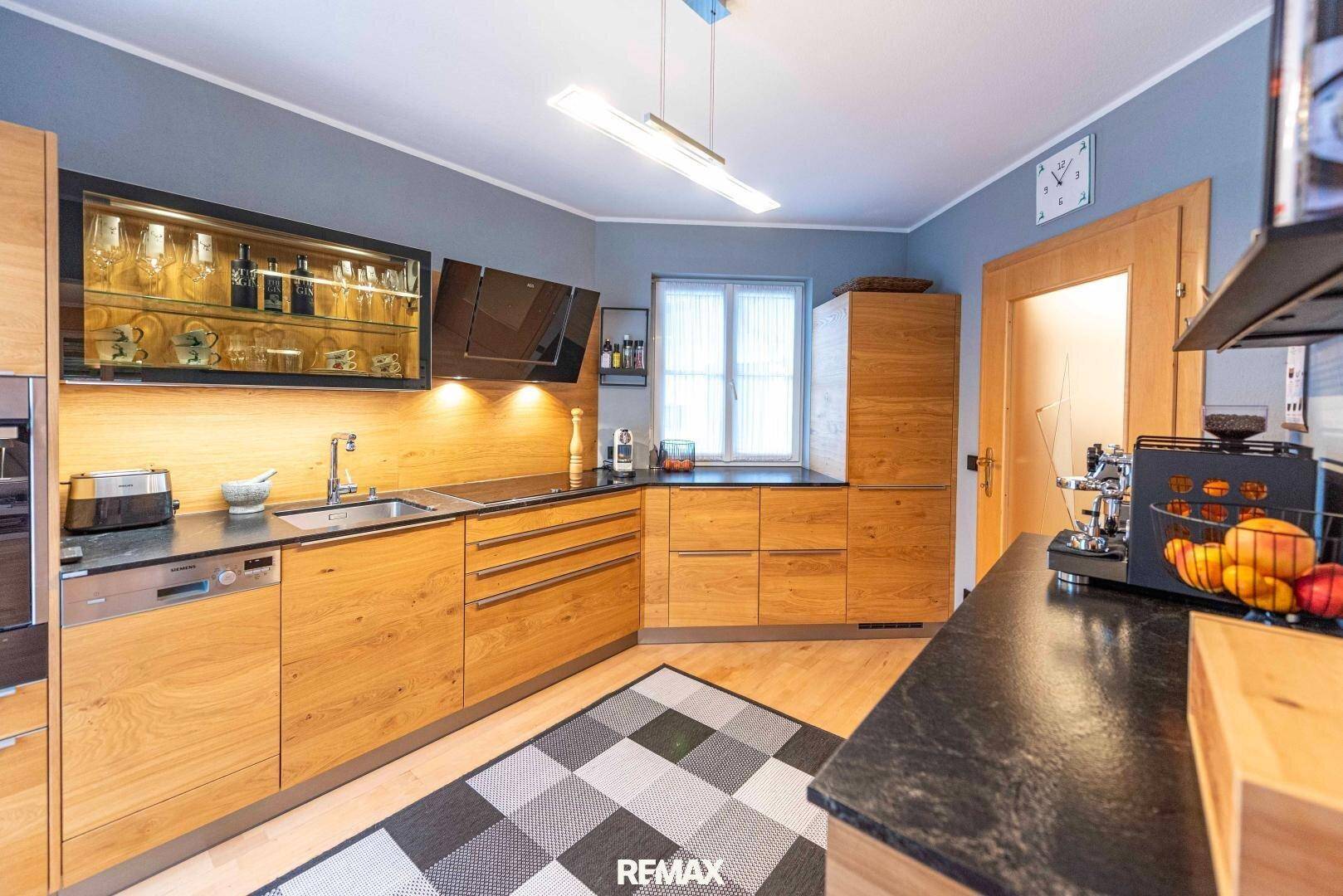 Moderne Küche mit Holzfronten, dunklen Arbeitsplatten und integrierten Geräten.