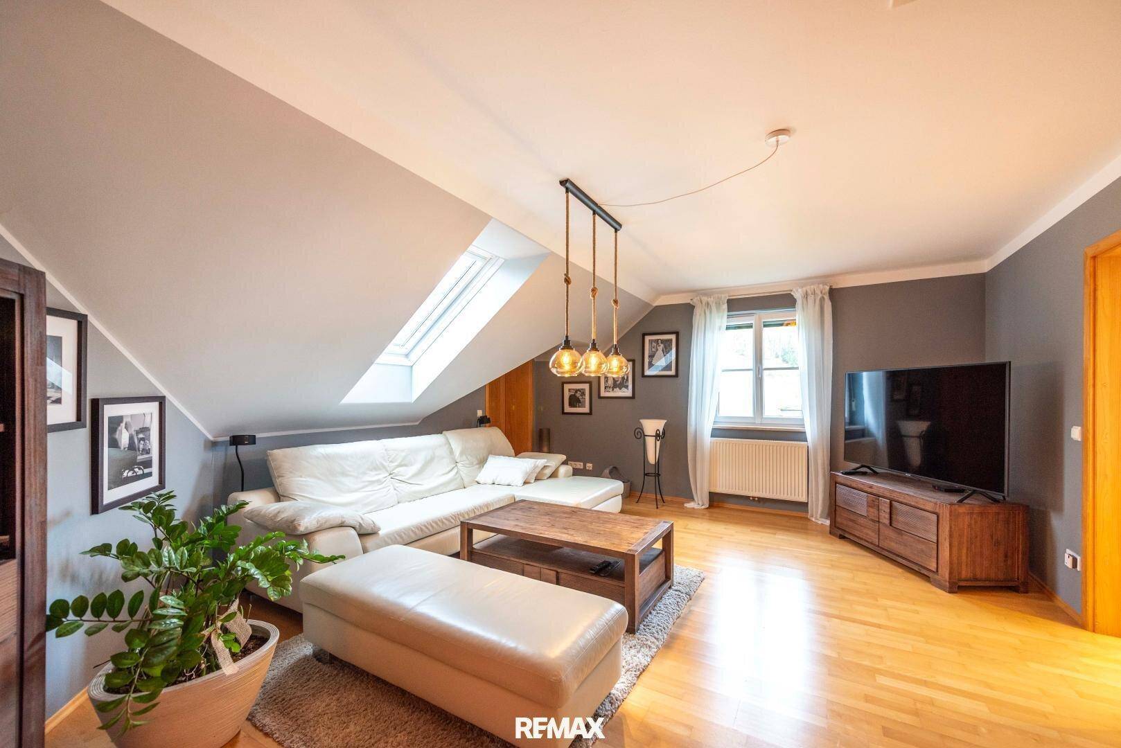 Helles Wohnzimmer im Dachgeschoss mit Schrägdecke, Dachfenster und Holzboden.