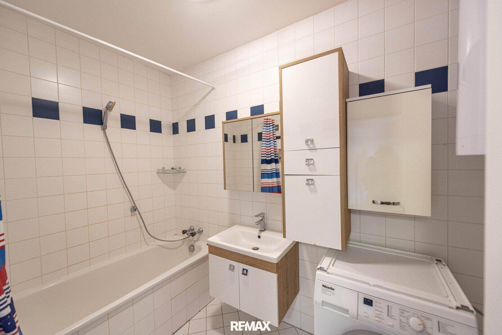 Badezimmer mit Badewanne, Waschbecken, Spiegelschrank und einer Waschmaschine.