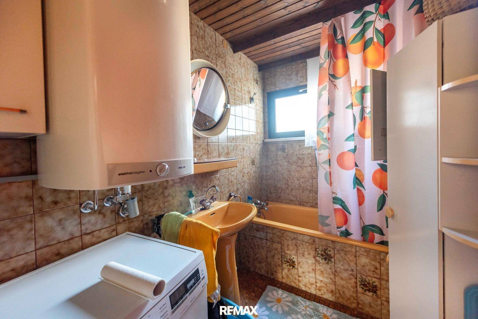 Badezimmer im Stil der 80er Jahre mit gelben Fliesen, Badewanne und einem kleinen Fenster.