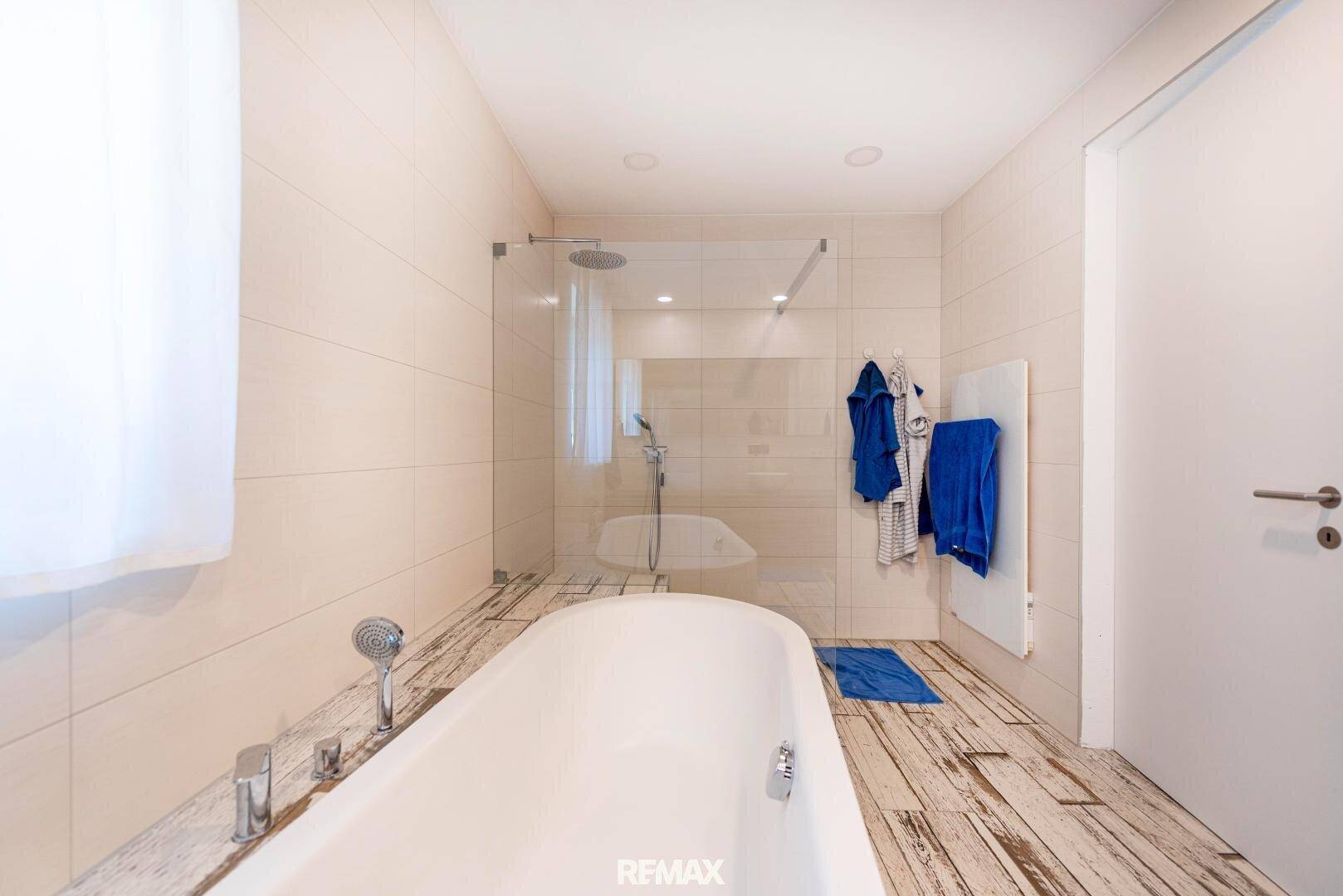 Elegantes Badezimmer mit begehbarer Dusche, Regendusche und beheiztem Handtuchhalter.