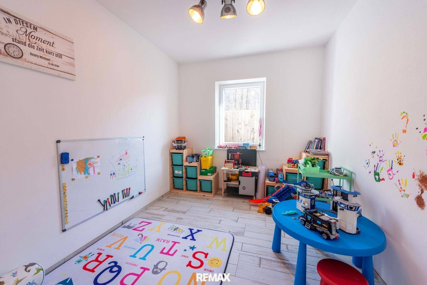 Helles Kinderzimmer mit Spielzeug, kleinem Tisch und Fenster, ideal zum Spielen und Lernen.
