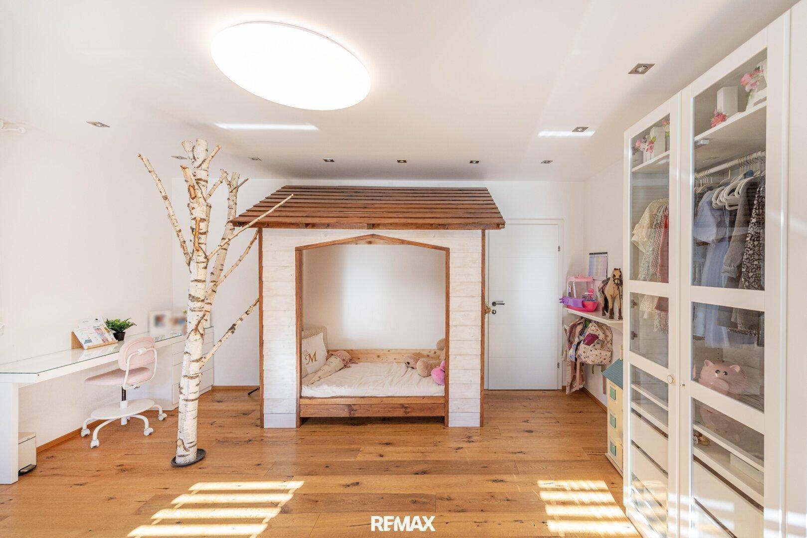 Kinderzimmer mit einzigartigem Hausbett, Schreibtisch und Kleiderschrank mit Glasfronten.