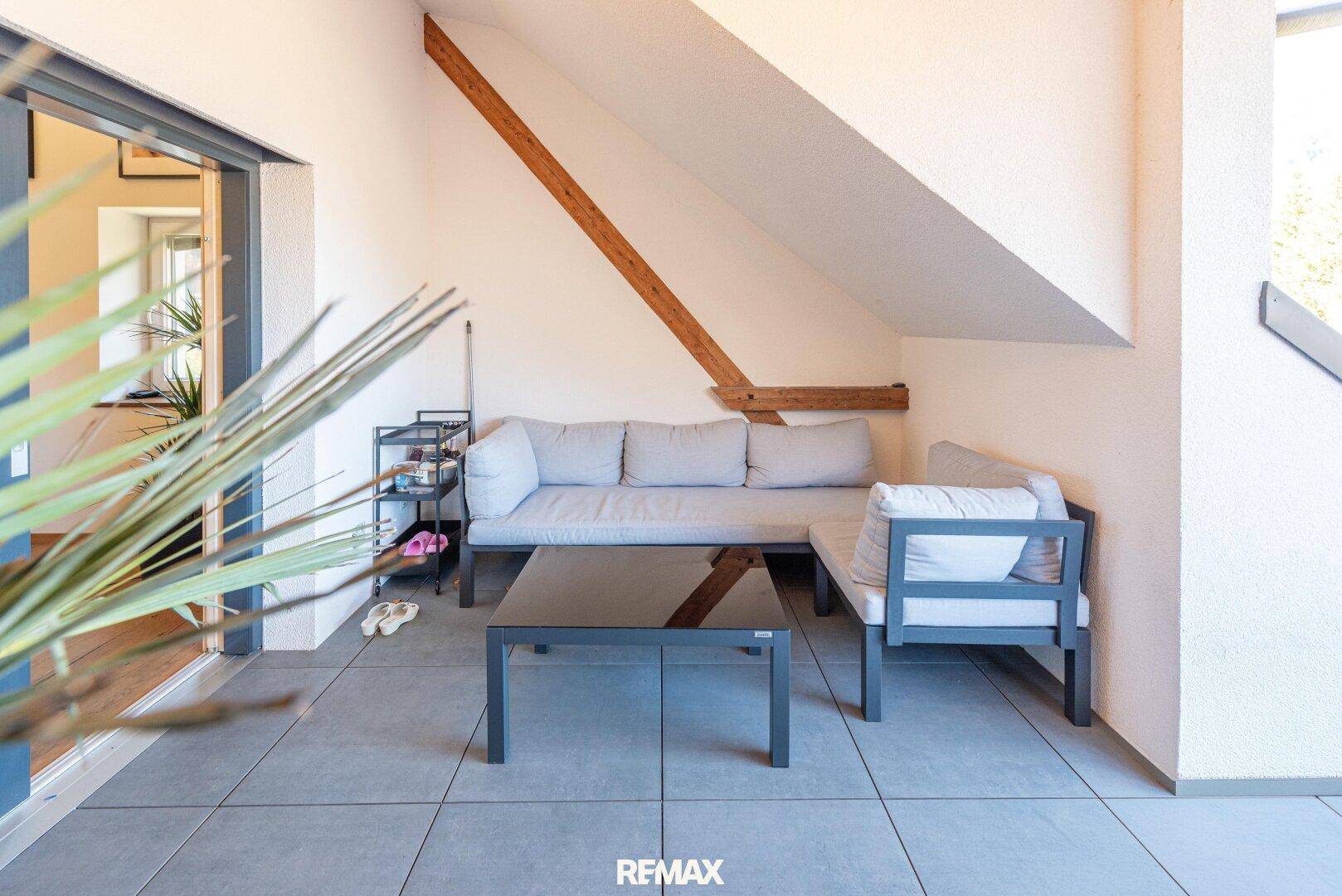 Gemütliche Terrasse mit modernen Outdoor-Möbeln und schrägen Dachbalken.