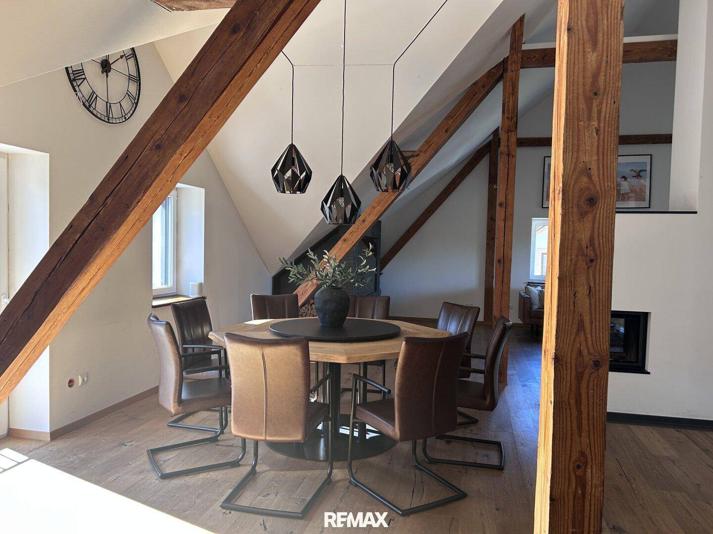 Stilvoller Essbereich mit Holztisch, Lederstühlen und modernen Pendelleuchten unter Holzbalken.