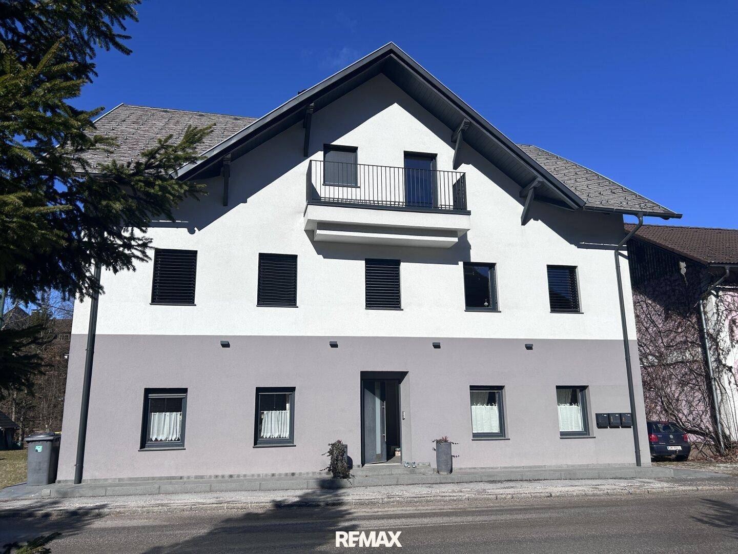 Frontansicht des modernen Gebäudes mit zweifarbiger Fassade und Haupteingang.