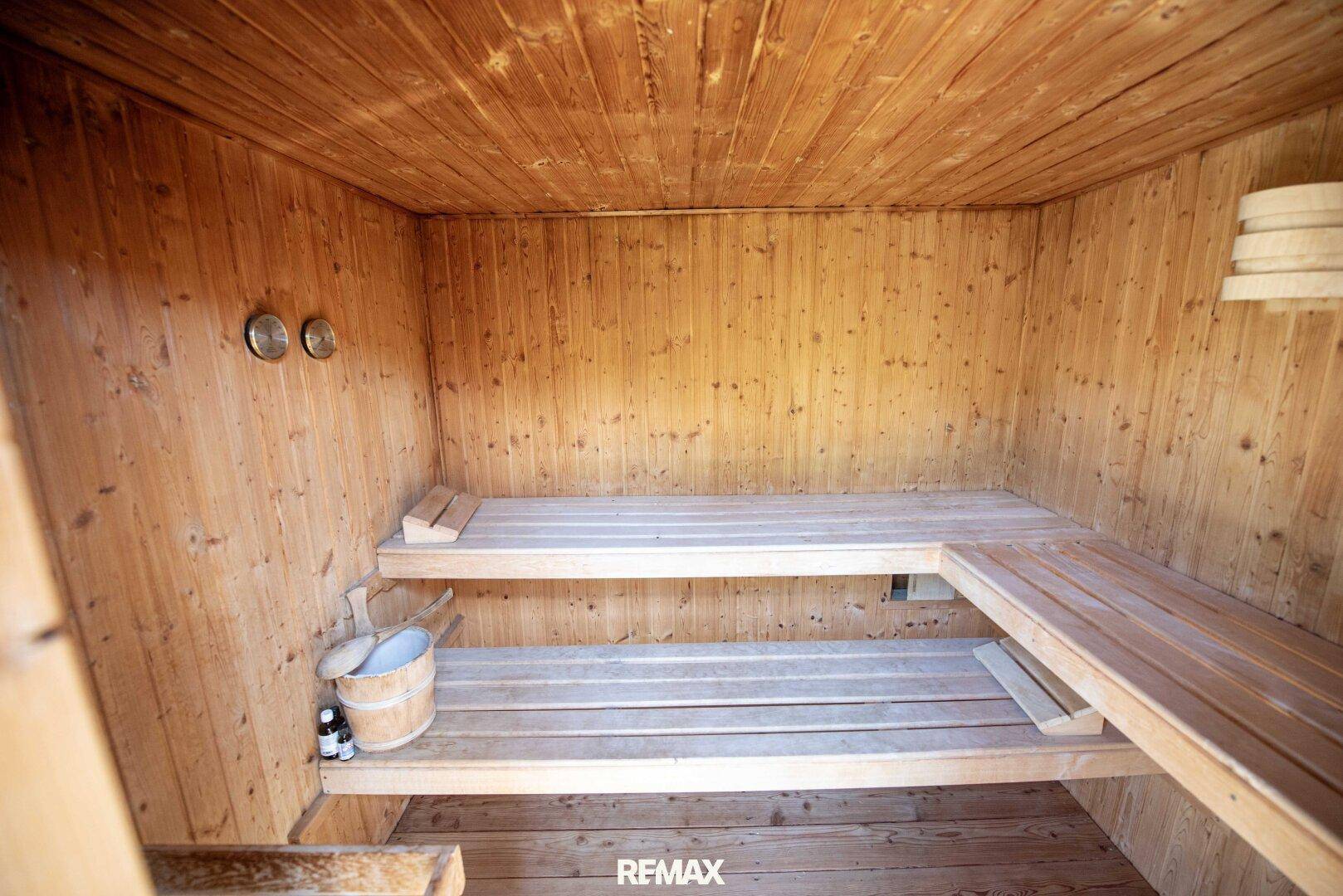 Traditionelle Holzsauna mit Bänken und Eimer, bereit für entspannende Momente.