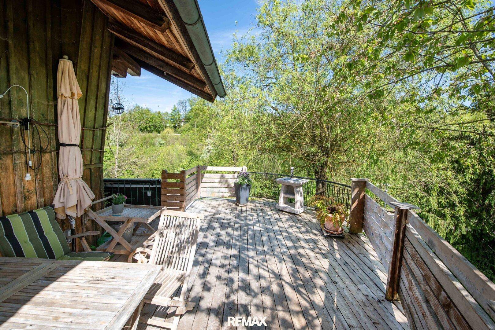 Großer Holz-Balkon mit Sitzgelegenheiten und weitem Blick ins Grüne.