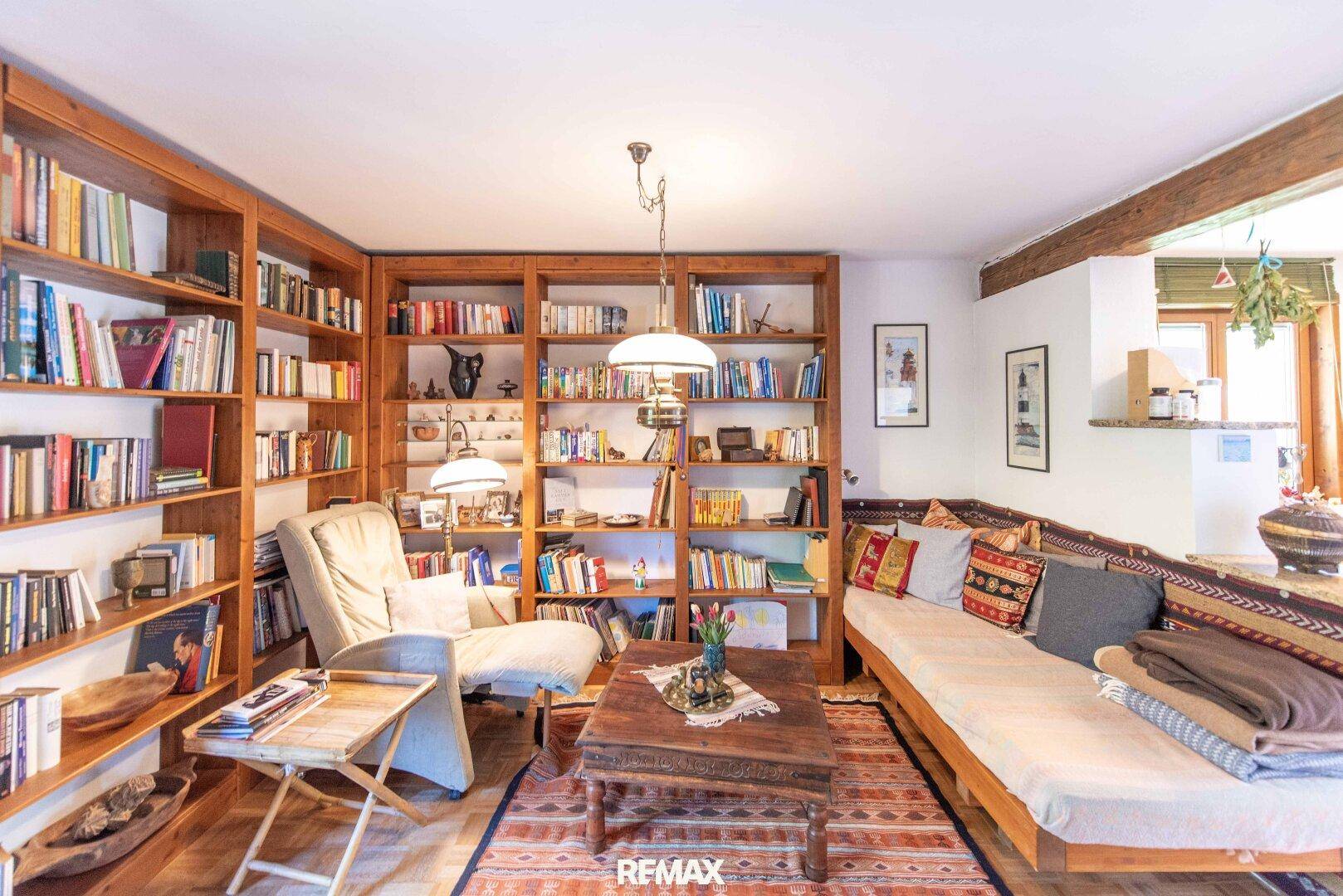 Wohnzimmer mit großen Bücherregalen, gemütlichem Sofa und traditionellem Teppich.