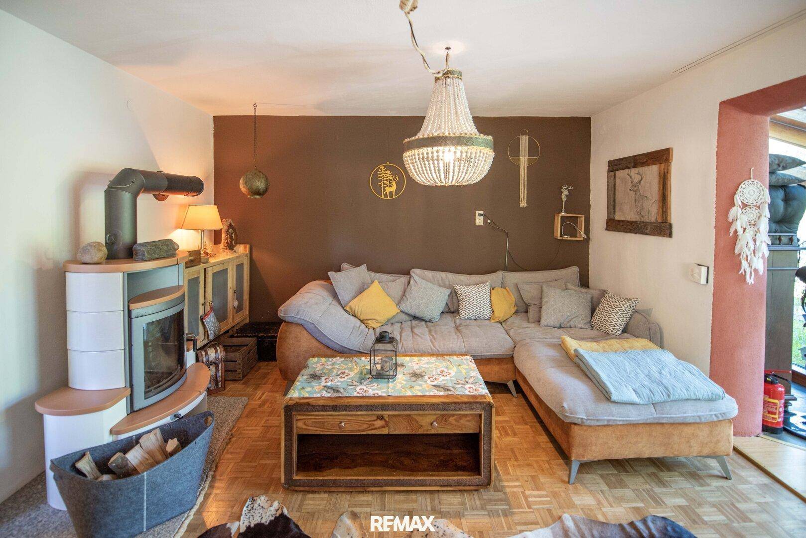 Einladendes Wohnzimmer mit modernem Kaminofen, bequemer Eckcouch und Holzboden.