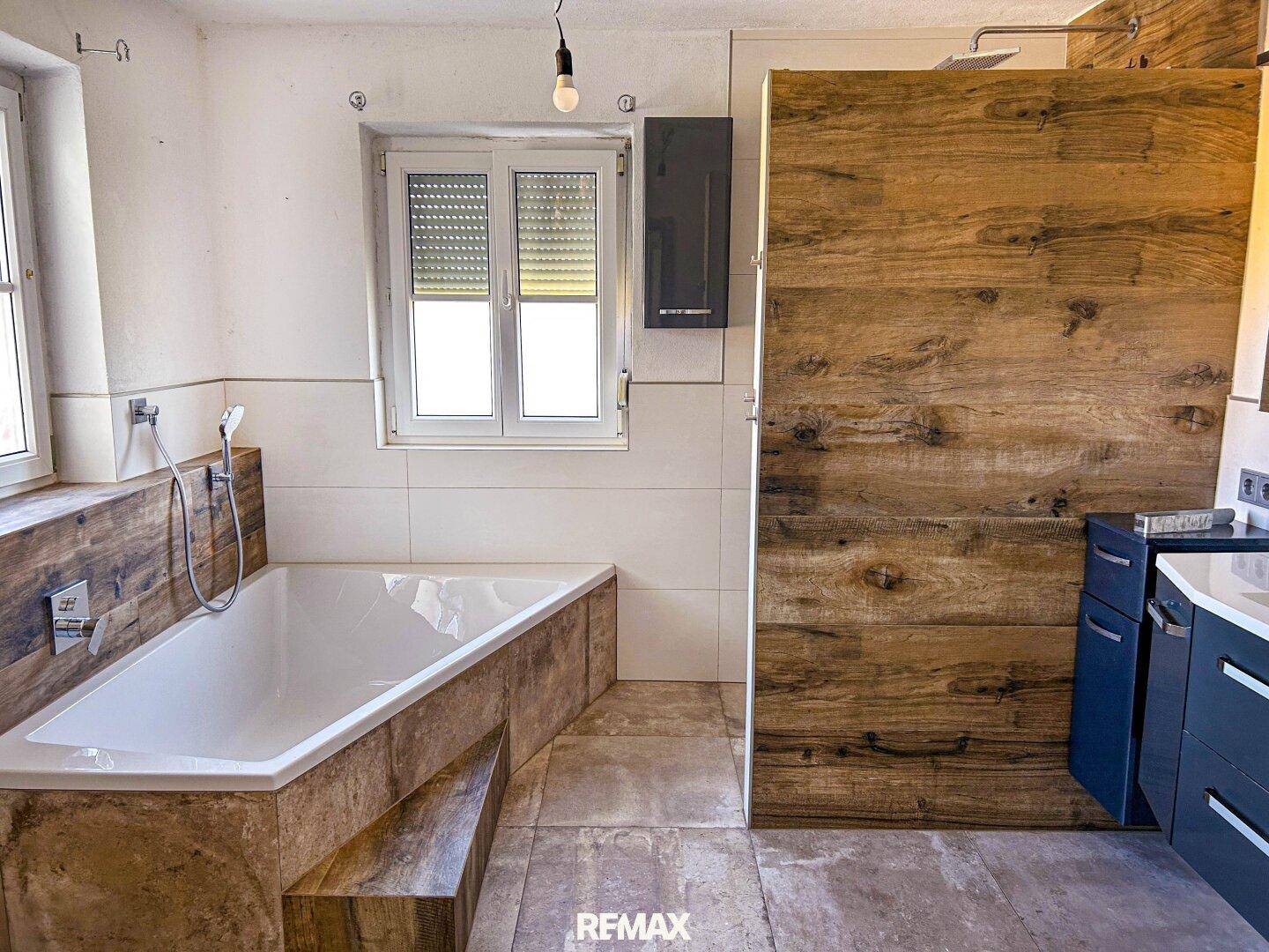 Badezimmer mit eingebauter Badewanne und einer begehbaren Dusche, verkleidet mit Holzoptik-Fliesen.