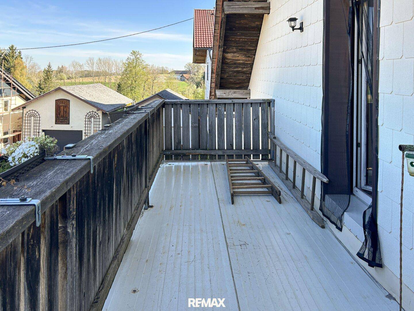 Rustikaler Holzbalkon mit Blick auf die umliegende ländliche Landschaft und grüne Hügel.