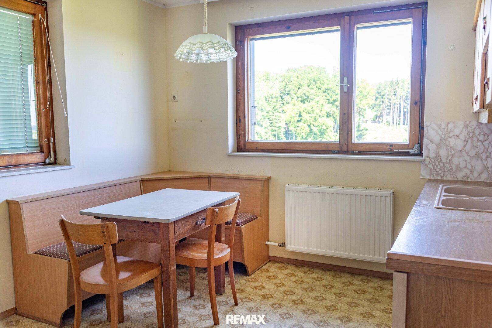 Gemütliche Essküche mit Eckbank, Holztisch und Fenster mit weitem Blick ins Grüne.