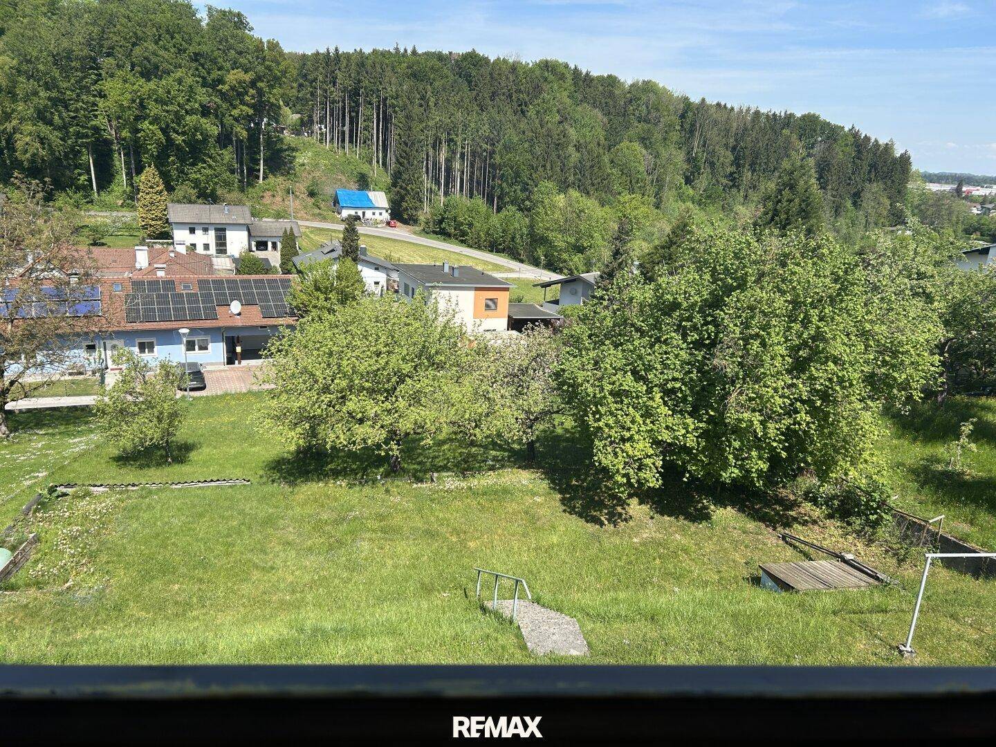 Weitläufiger Blick über grüne Hügel und Wälder mit weiteren Häusern in der Ferne.