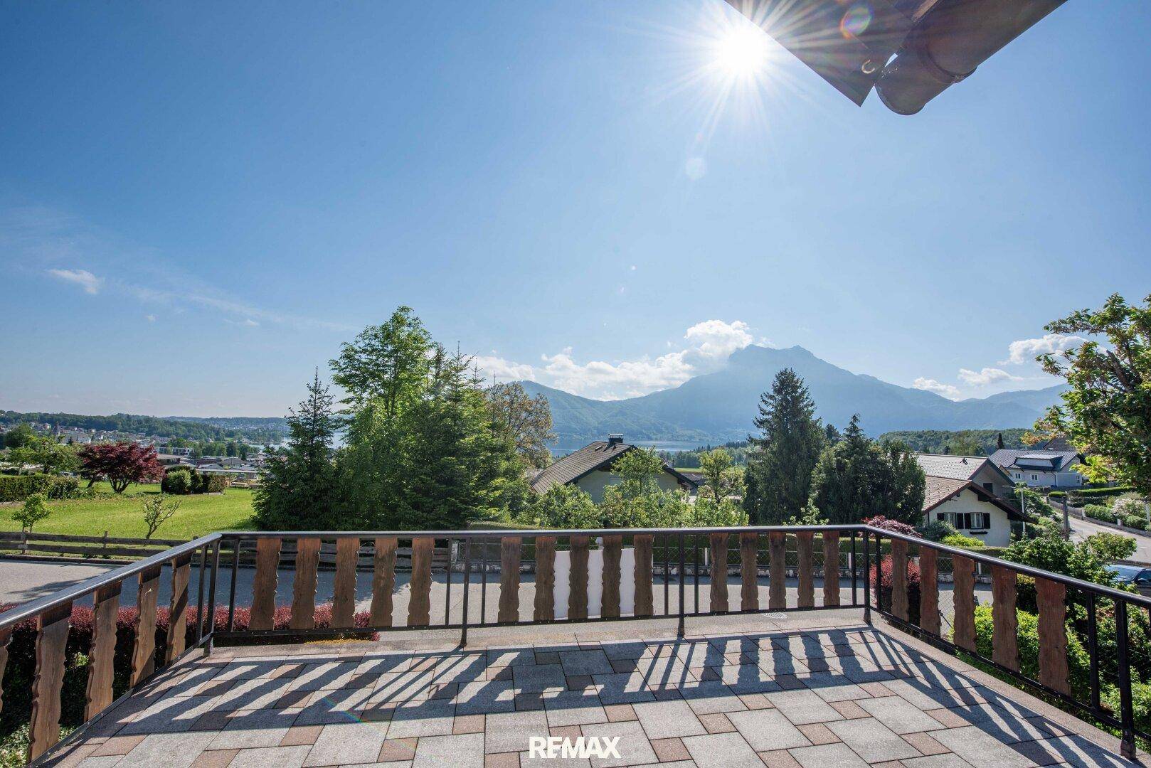 Geräumige Terrasse mit Holzbalkongeländer und weitem Blick auf Berge und See.