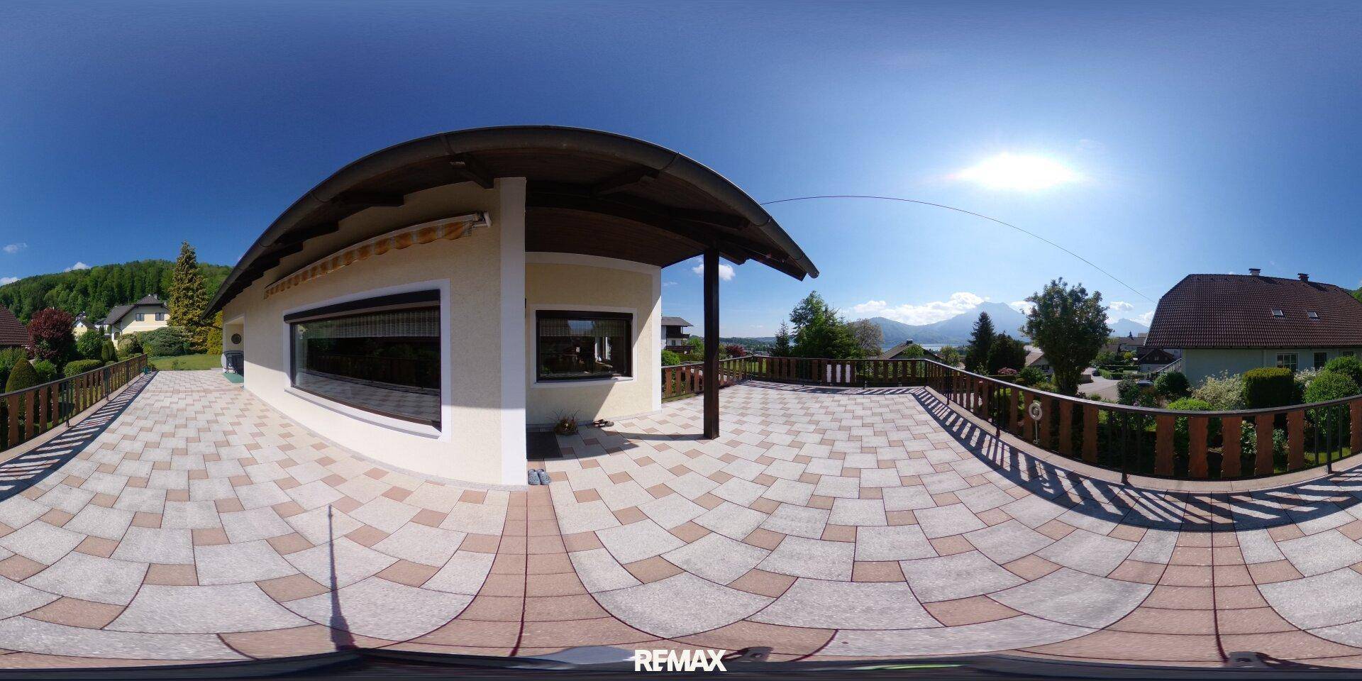 Weitläufige, geflieste Terrasse mit Überdachung und Panoramablick auf die umliegende Berglandschaft.