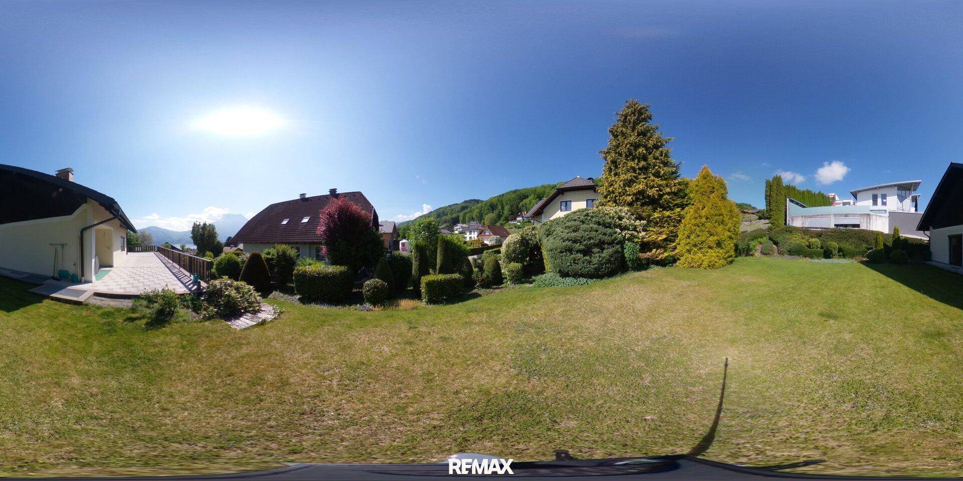 Großer, gepflegter Gartenbereich mit Rasenflächen, Hecken und Bäumen, umgeben von Natur.