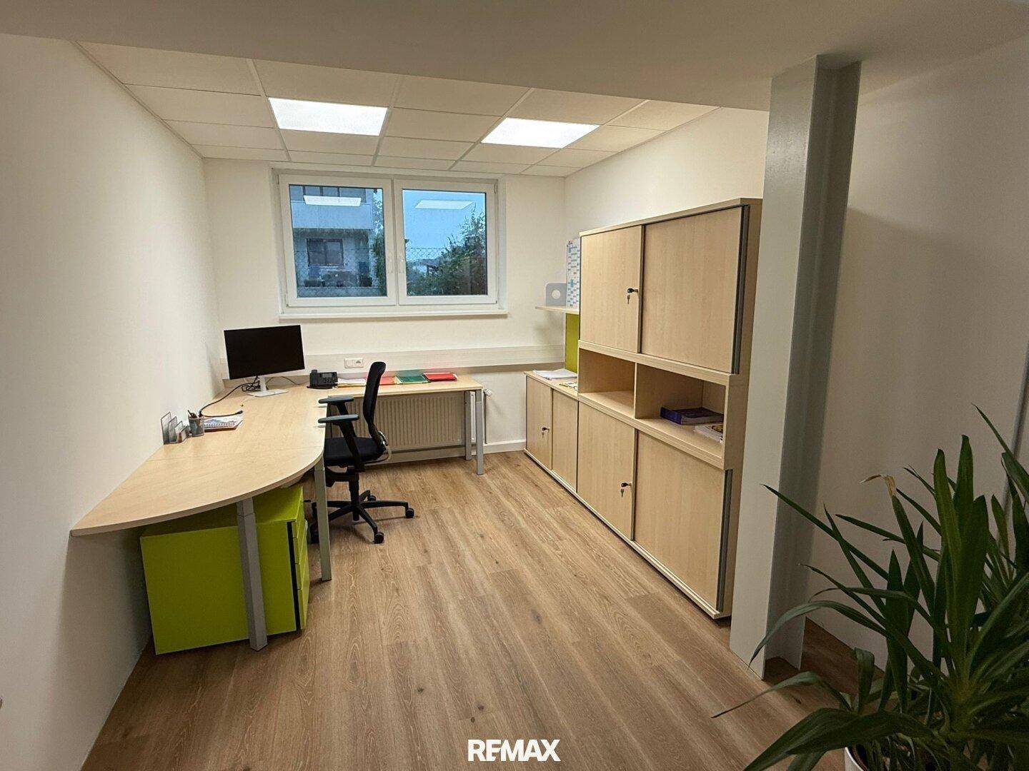 Helles Büro mit modernem Schreibtisch, Bürostuhl und Holzschränken, gut beleuchtet durch ein Fenster.
