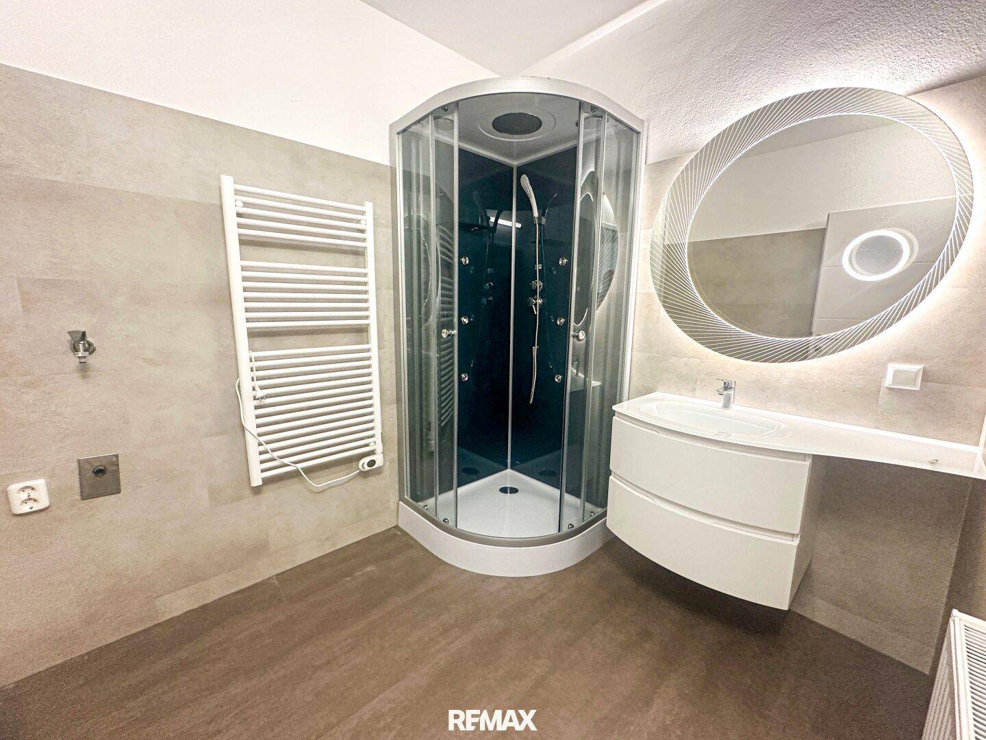 Modernes Badezimmer mit Duschkabine, Einzelwaschbecken und beheiztem Handtuchhalter.