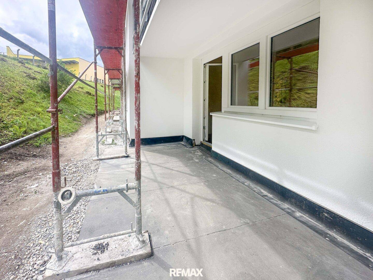 Unfertige Terrasse mit Betonboden und Gerüst, die auf Fertigstellung wartet.