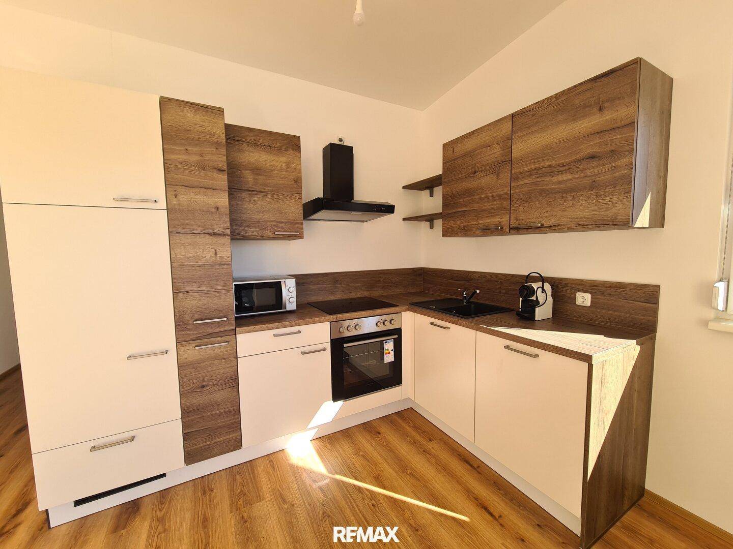 Moderne Einbauküche mit hellen und holzfarbenen Fronten, ausgestattet mit allen notwendigen Geräten.