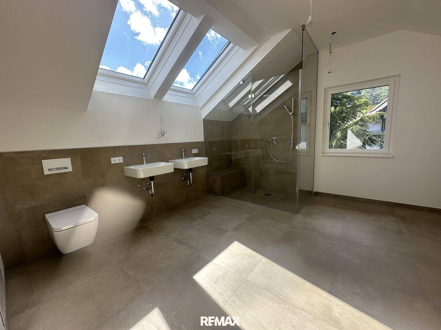 Modernes Badezimmer im Dachgeschoss mit doppelten Waschbecken, begehbarer Dusche und Dachfenstern.