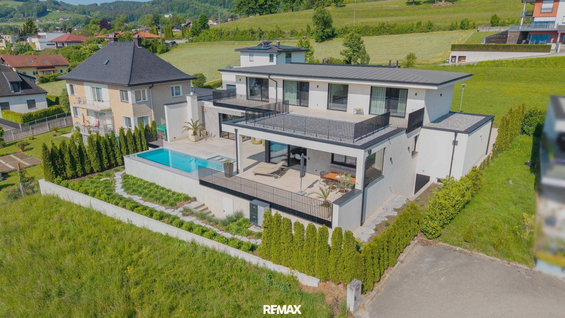 Beeindruckende moderne Villa mit Pool und gepflegtem Garten in idyllischer Hügellandschaft.
