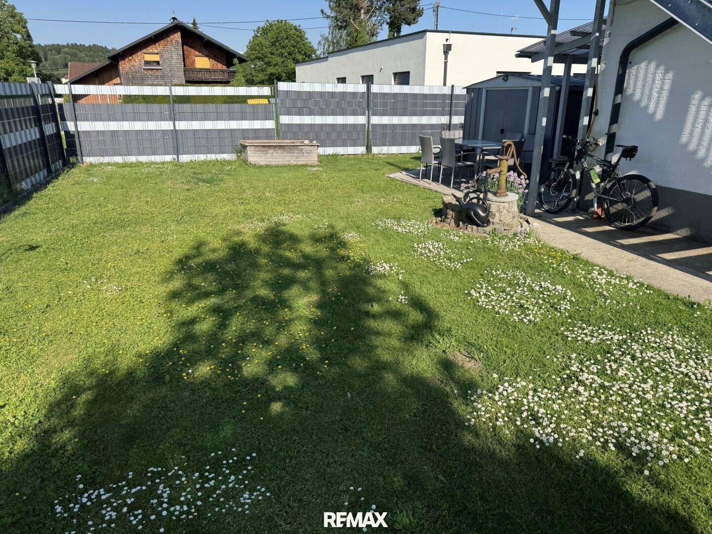 Grüner Garten mit Rasenfläche, Sitzgelegenheiten und einem kleinen Brunnen im Freien.