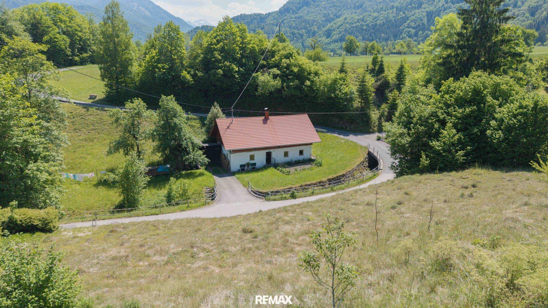 Freistehendes Haus in idyllischer Berglandschaft, umgeben von Wiesen und Bäumen.