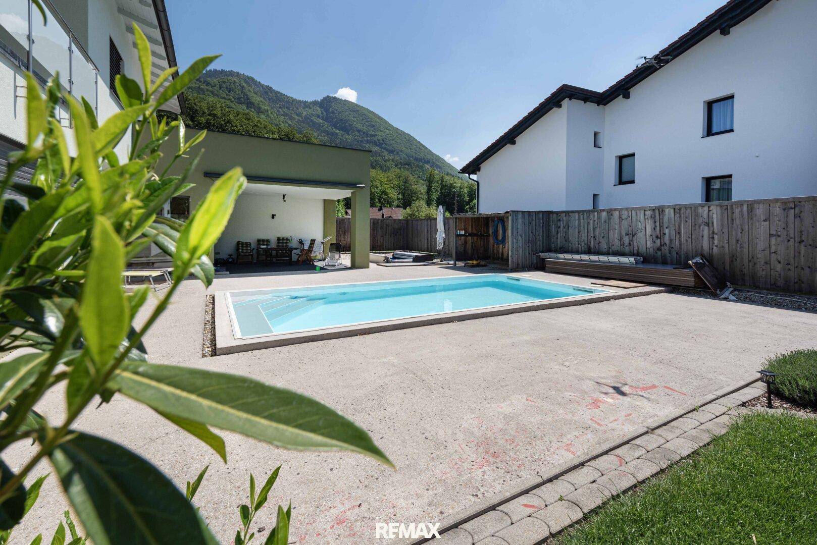 Außenbereich mit Swimmingpool und großzügiger Terrasse, umgeben von einer malerischen Bergkulisse.