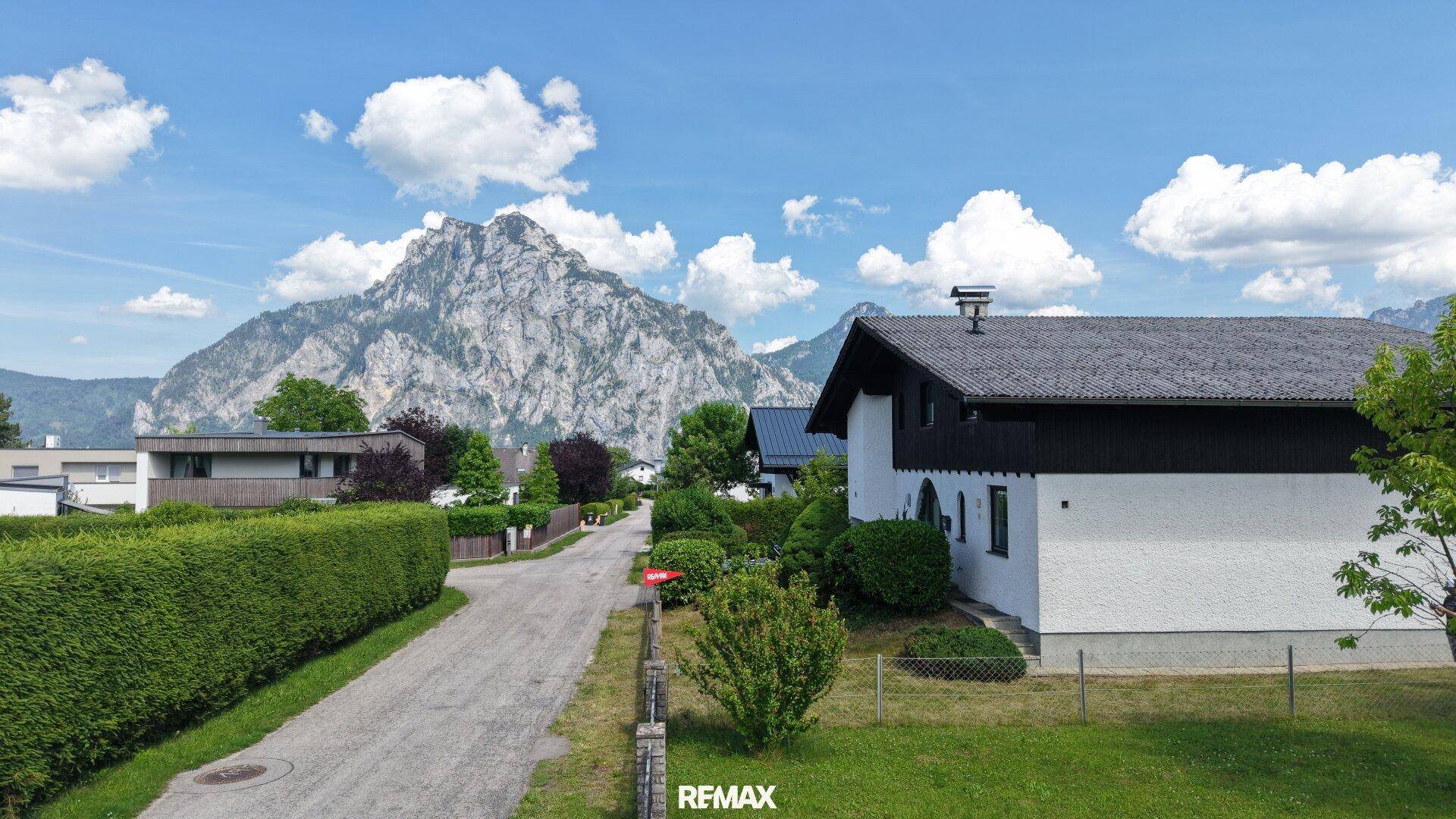 Ansicht des Hauses von der Straße aus, umgeben von Hecken und mit Bergblick.