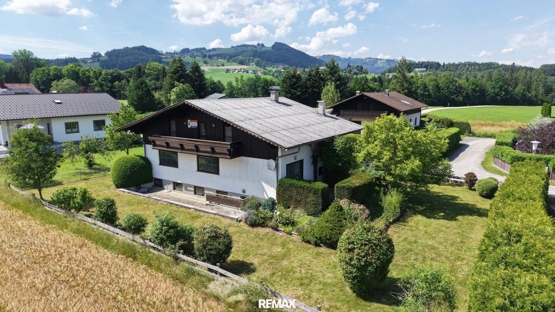 Weitläufige Luftaufnahme eines Einfamilienhauses mit großem Garten, umgeben von Feldern und Hügeln.