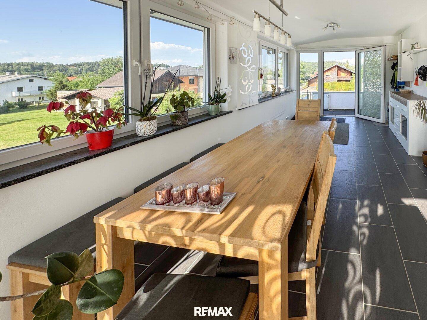 Heller Essbereich mit großem Holztisch, Fliesenboden und weitem Blick ins Grüne.