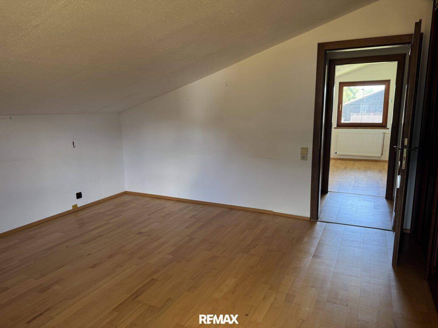 Schlafzimmer im Dachgeschoss mit Holzboden und schrägen Wänden, bietet viel Platz.