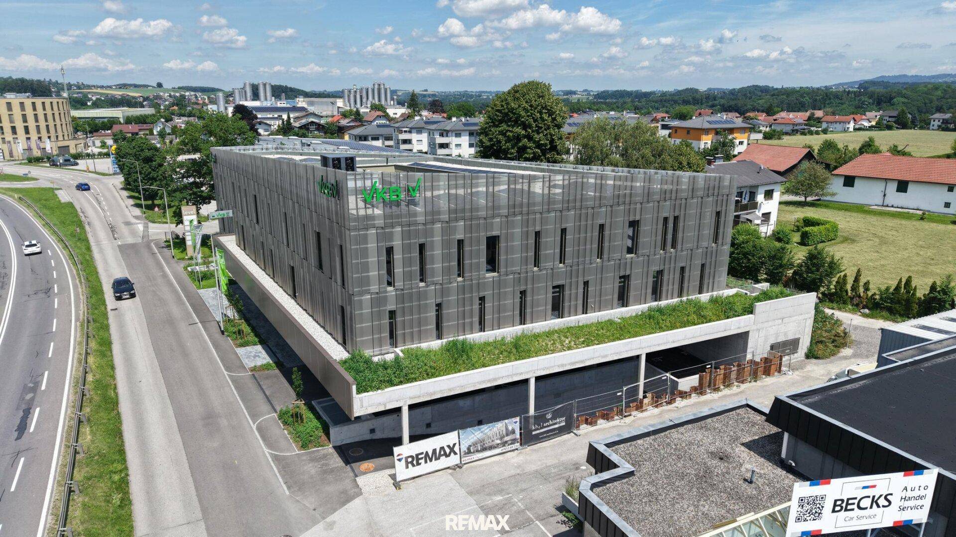 Weitläufige Luftaufnahme des modernen Bürokomplexes mit begrünten Flächen und umliegender Bebauung.
