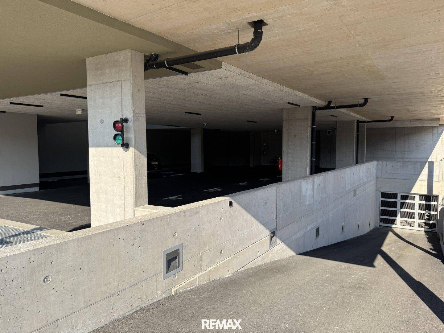 Einfahrt zur Tiefgarage mit Ampelsystem und Betonwänden, gut zugänglich.