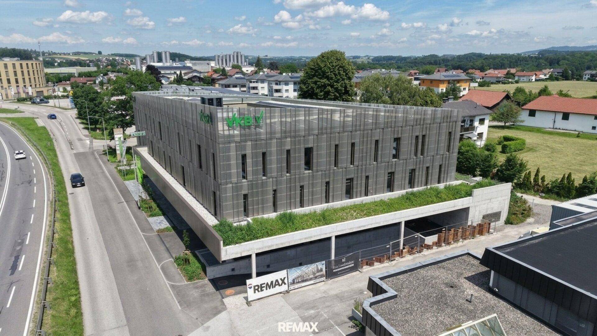 Weitläufige Luftaufnahme des modernen Geschäftsgebäudes mit Tiefgarage und umliegender Infrastruktur.