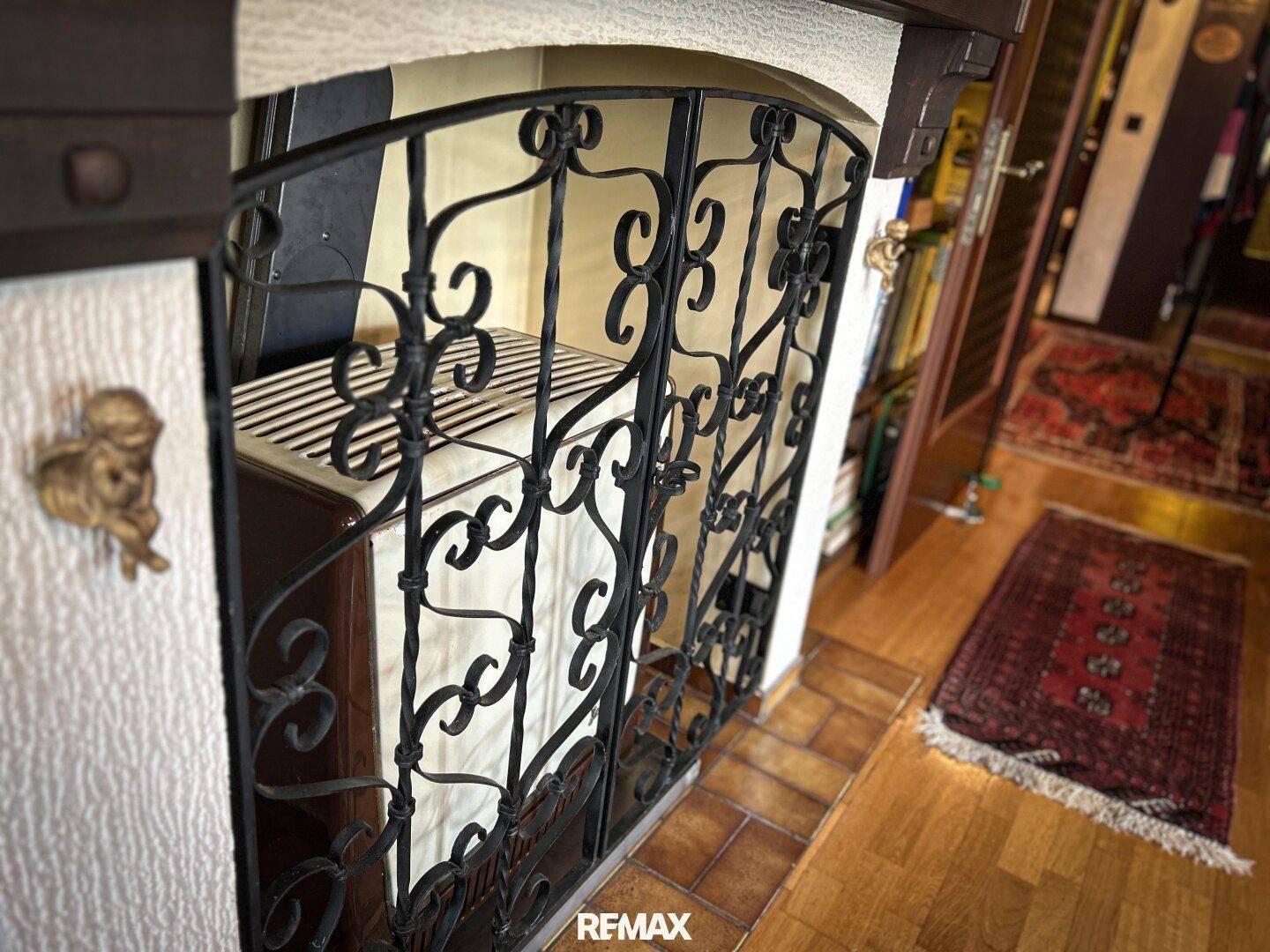 Traditioneller Kachelofen mit schmiedeeisernem Gitter, der Wärme und Gemütlichkeit spendet.