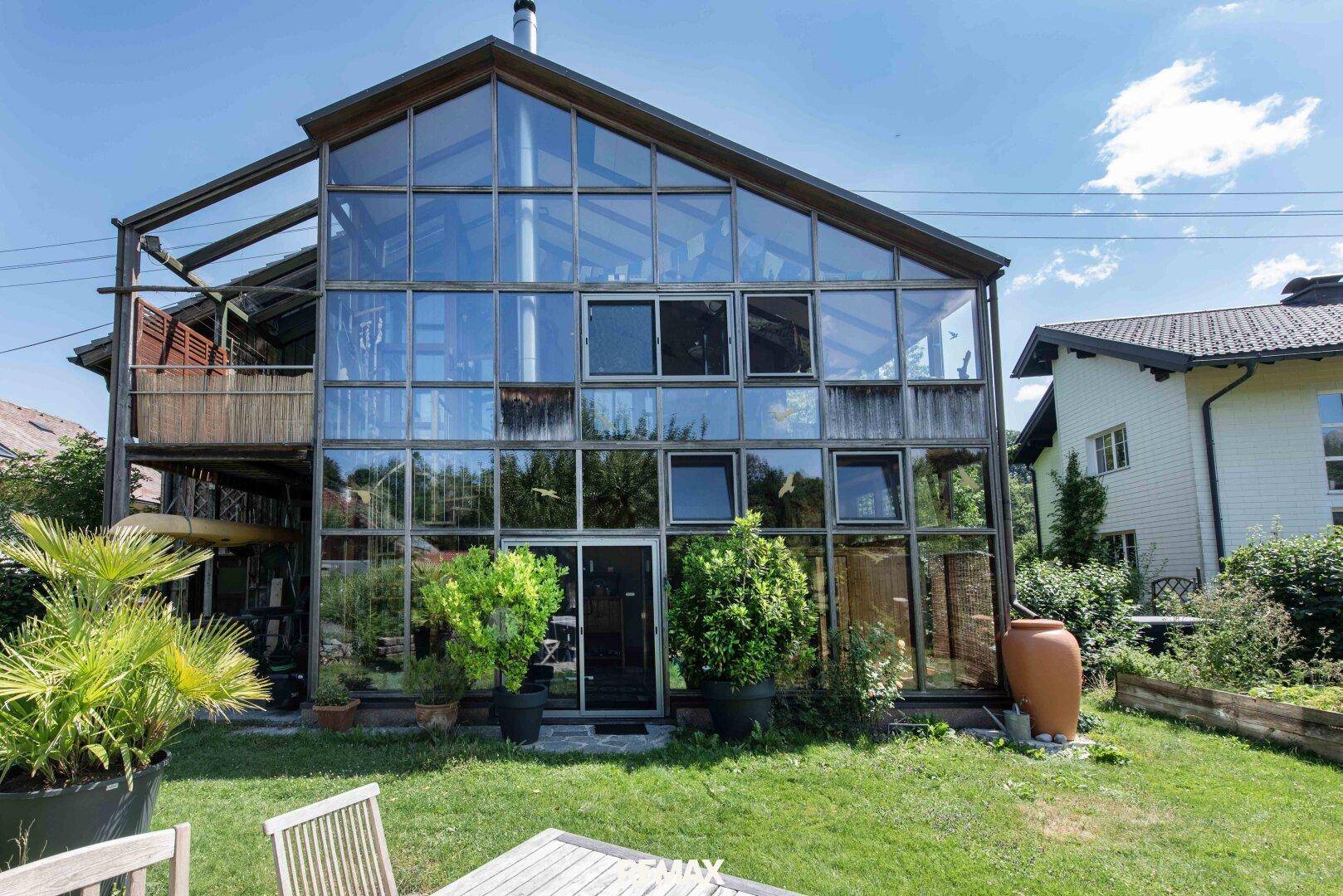 Rückseite des Hauses mit beeindruckender, mehrstöckiger Glasfassade und gepflegtem Rasenbereich.