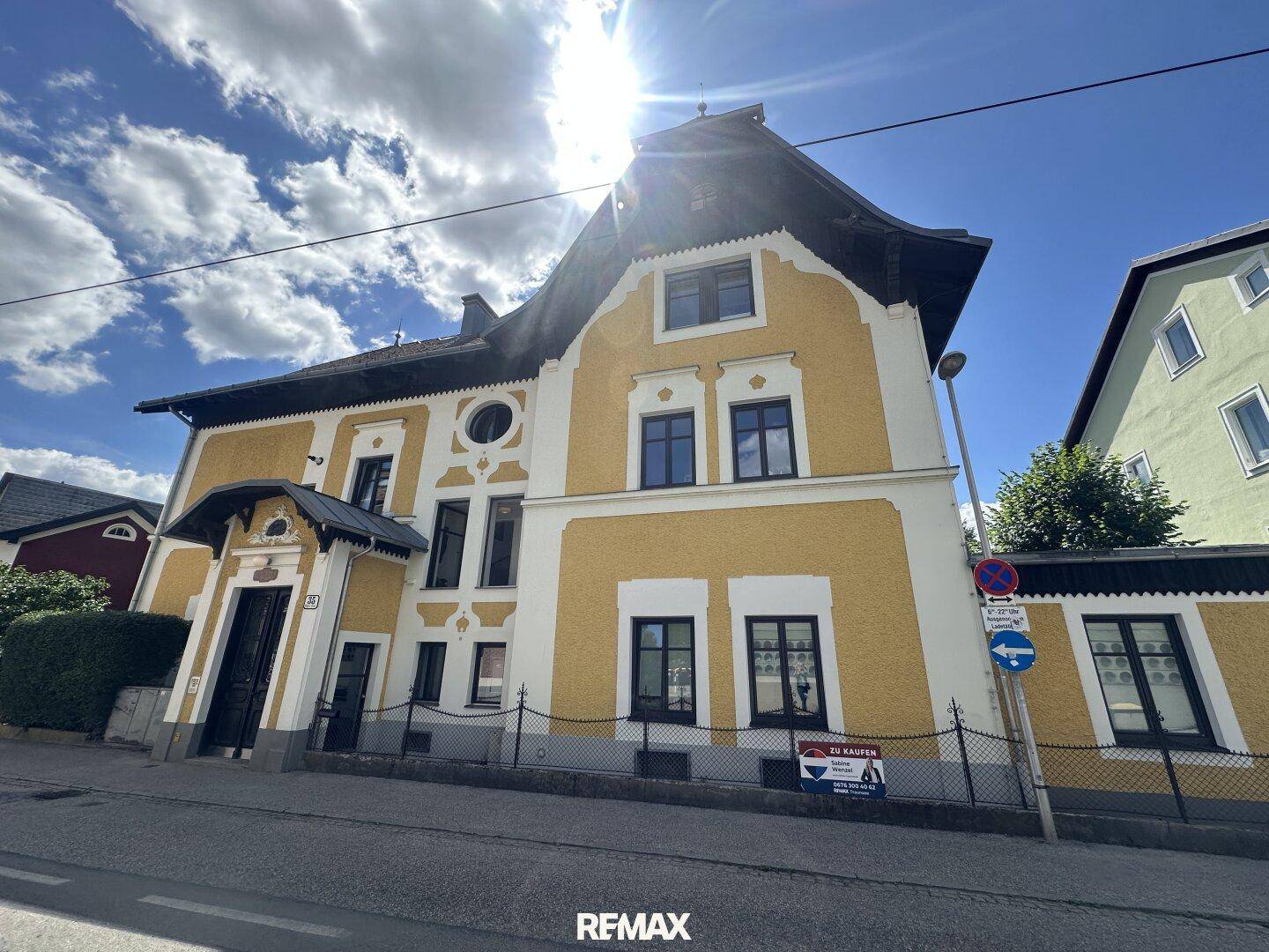 Historisches Gebäude mit gelber Fassade und traditioneller Architektur unter blauem Himmel.